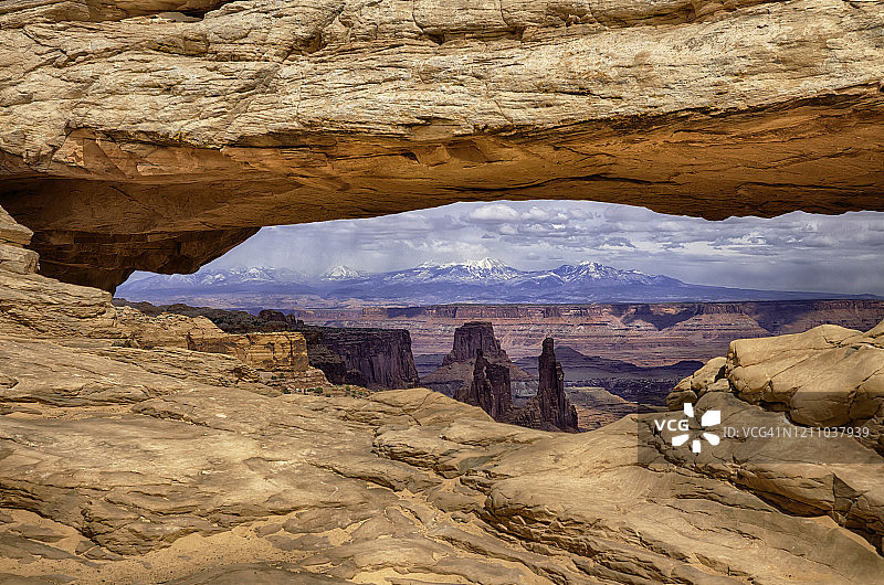 峡谷地国家公园的台地拱门的HDR图像，以崎岖的沙漠景观和雪山为背景图片素材