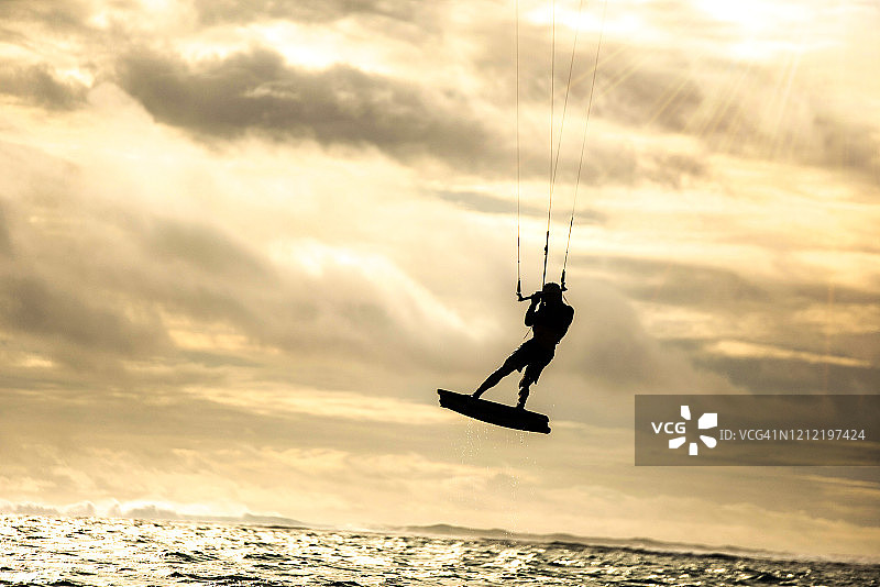 风筝滑板时一个人在空中飞行的剪影。图片素材