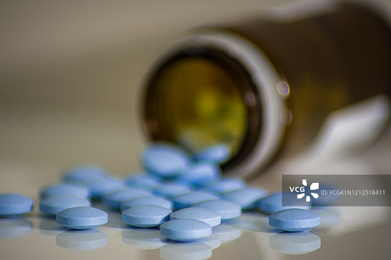 蓝色的药片从棕色的玻璃里洒出来，这些小药片有助于抗病毒图片素材