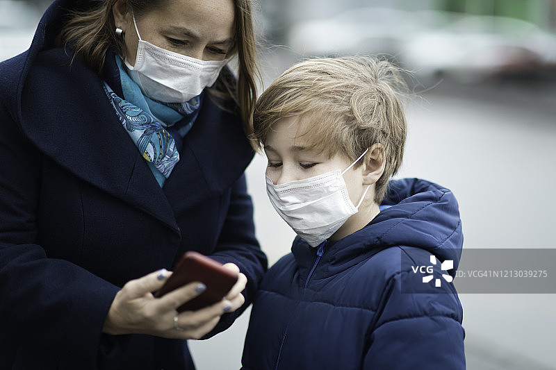 家人戴着医用防护口罩和智能手机图片素材