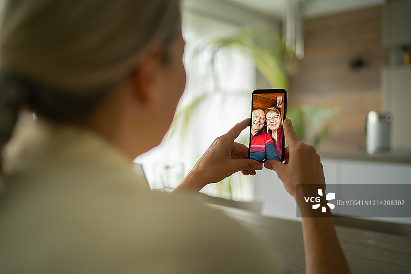 微笑的成年父母与女儿通过手机视频通话图片素材