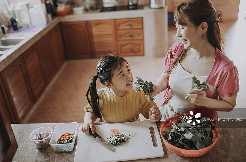 一位亚洲华人家庭主妇与她的女儿在厨房准备食物图片素材