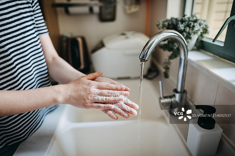一名妇女保持双手卫生，在水槽中用肥皂洗手的剪发镜头图片素材