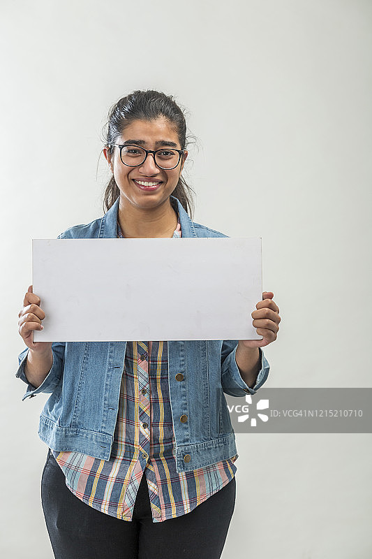 一个戴着眼镜，拿着空白牌子的印度少女图片素材
