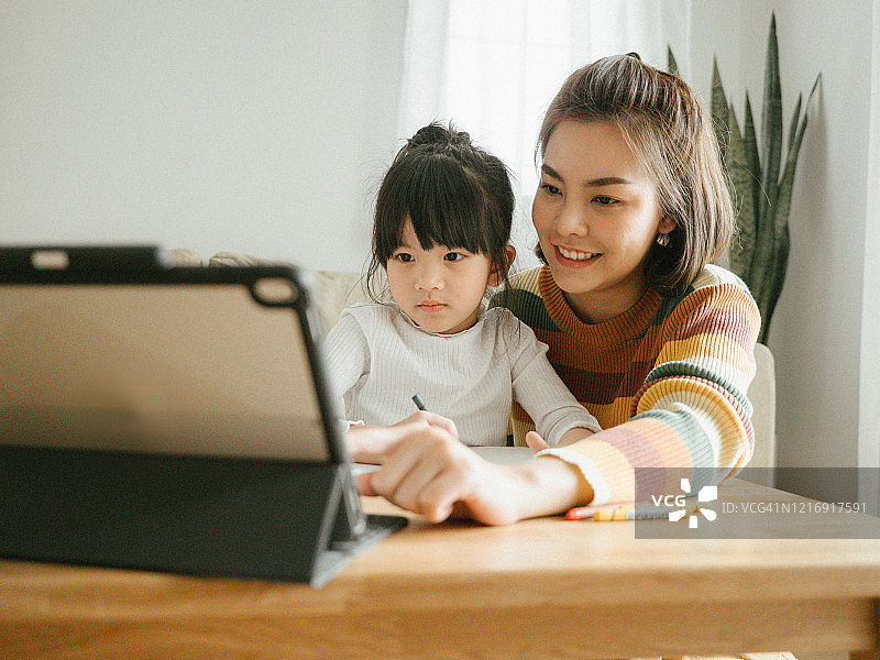 亚裔女儿在家和母亲一起参加网络课程。图片素材