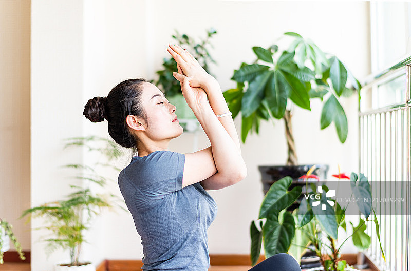 一个亚洲年轻女子在客厅里练瑜伽图片素材