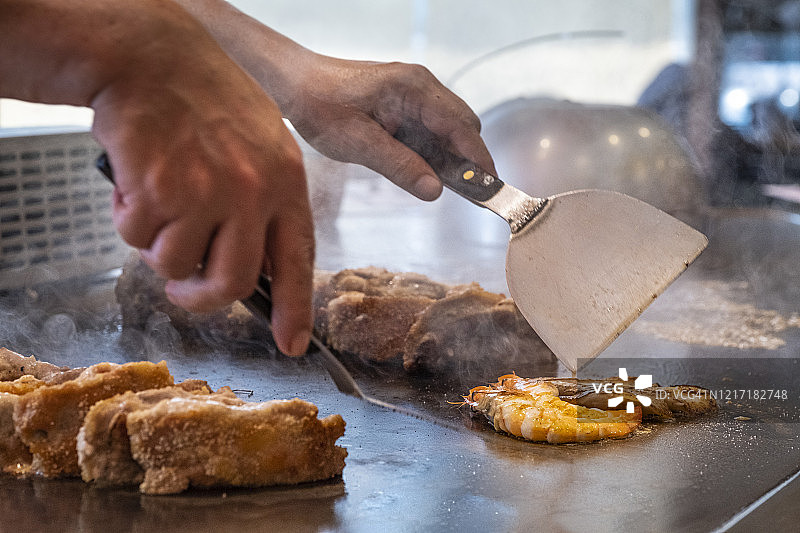 日本厨师烹饪鸡肉和海鲜在铁板烧餐厅图片素材