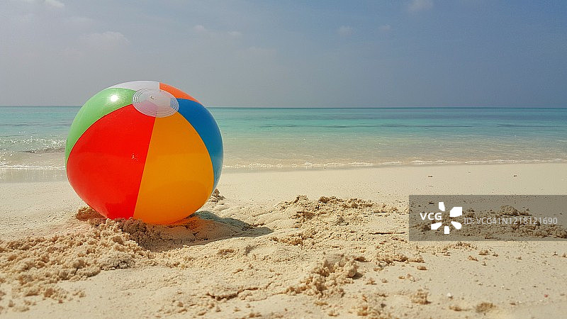 彩色的沙滩球堆积在白色沙滩上未经海浪在一个炎热的夏天，拷贝空间图片素材