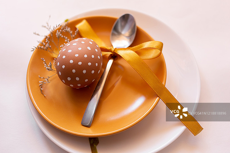 复活节时，在黄白相间的盘子上涂上各种白色图案的棕色彩蛋，并配上香草。带黄色丝带的勺子。传统的东欧文化。俯视图图片素材
