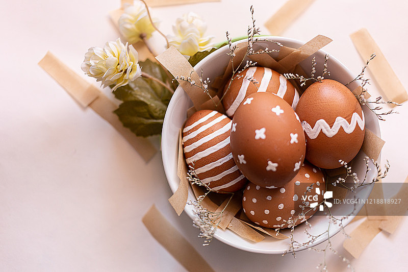 复活节时在碗里涂上各种白色图案的棕色蛋。天然自制的彩色鸡蛋。复活节的概念。前视图。白色背景。传统的东欧正统文化图片素材