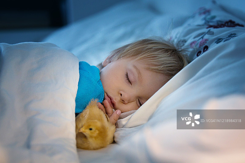 一个蹒跚学步的小孩，和一个小妞睡在床上图片素材