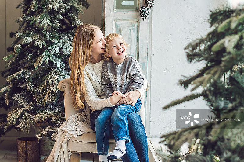 快乐的妈妈和可爱的男孩庆祝圣诞节的肖像。新年假期。幼童和妈妈在节日装饰的房间里的圣诞树和装饰品图片素材