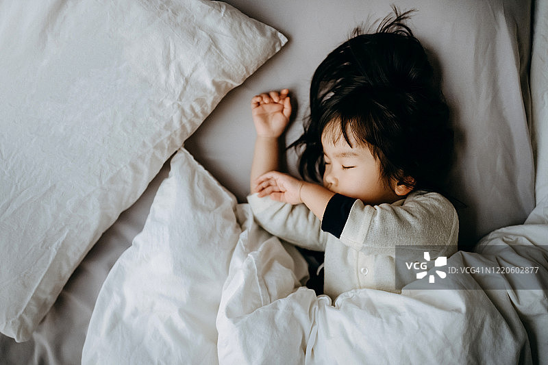 亚洲小女孩睡在传统的日式蒲团上，躺在家里的榻榻米垫子上图片素材