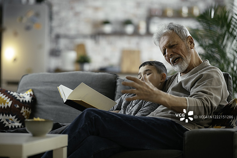 爷爷和孙子一起看书。图片素材