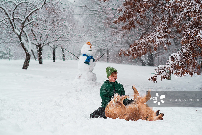 美国，一个男孩和他的狗在雪地里玩耍图片素材