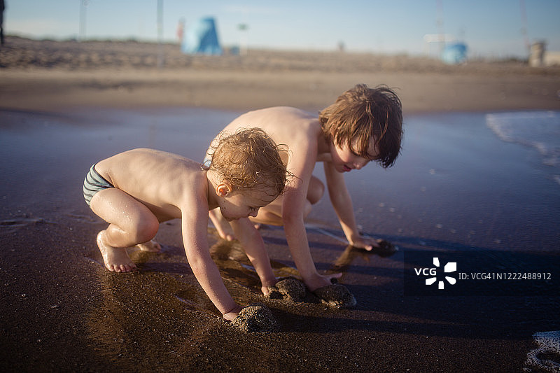 兄弟们在沙滩上玩沙子图片素材