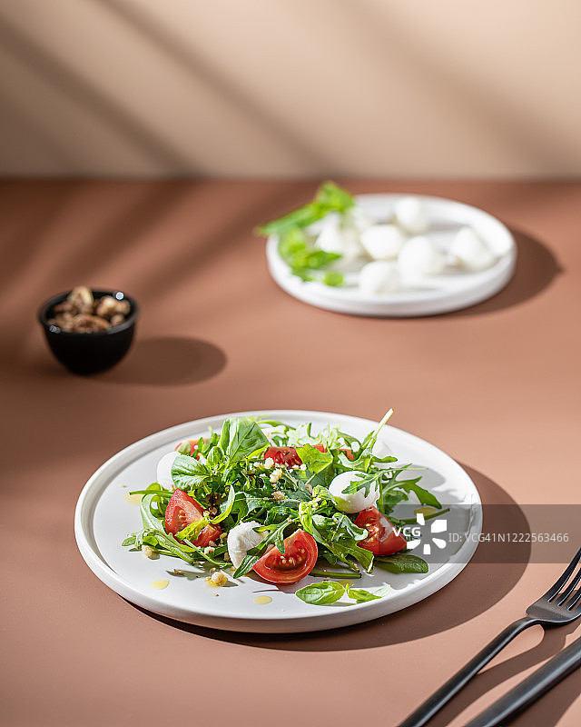 现代风格的绿色番茄沙拉，米色背景。健康的食物图片素材