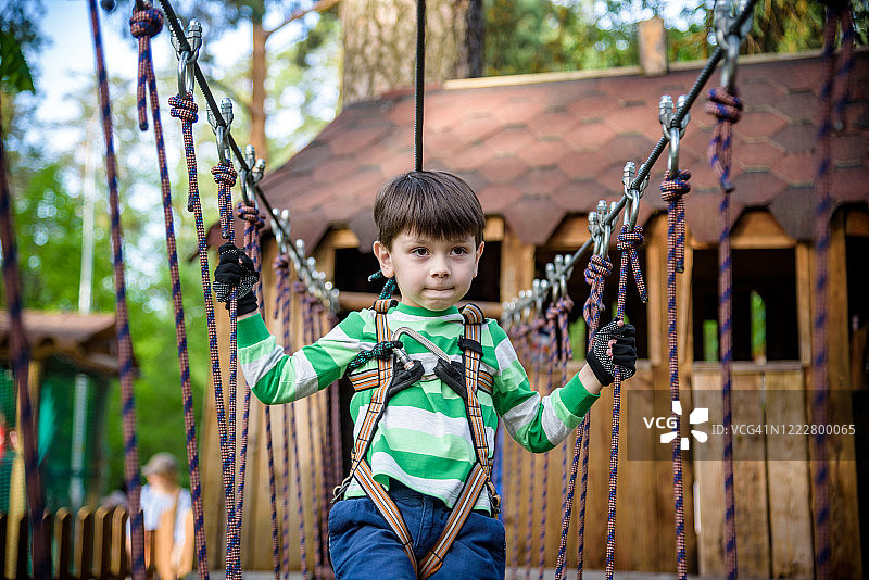 快乐的孩子在冒险公园玩，拿着绳子和爬木楼梯图片素材