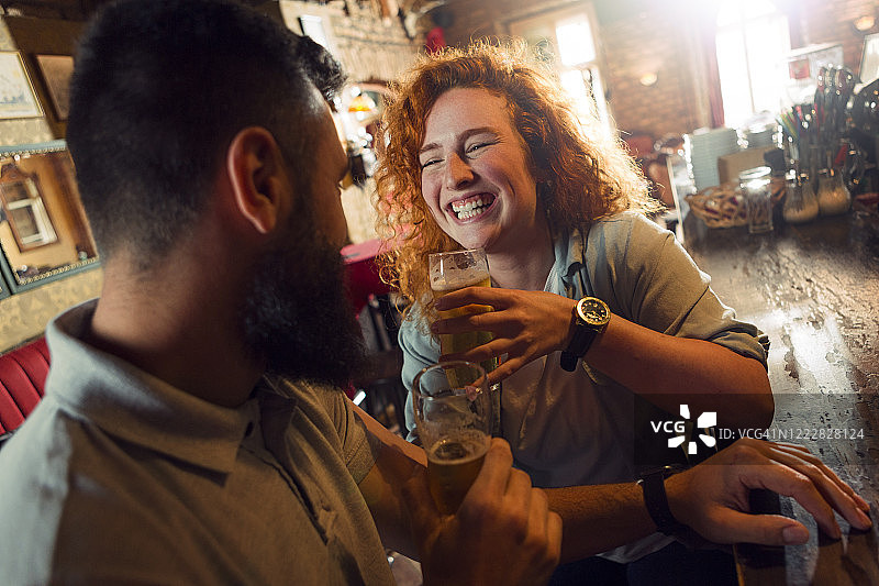年轻夫妇在酒吧里微笑着喝啤酒图片素材