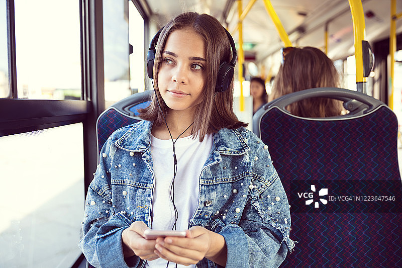 在公车上听音乐的体贴女孩图片素材