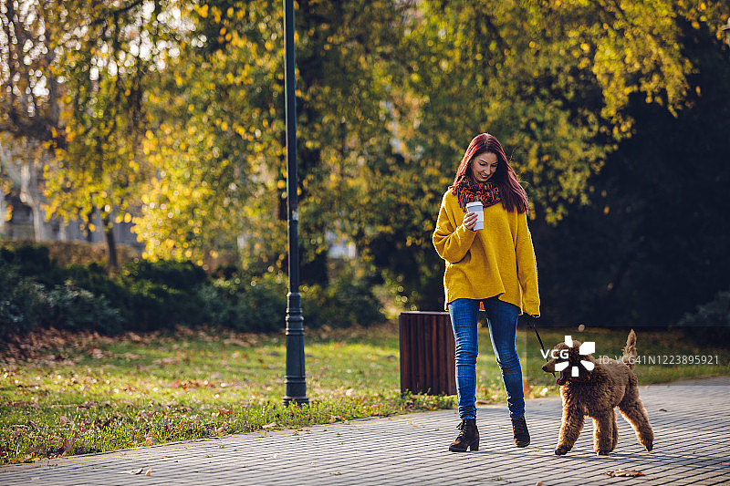 年轻女子与她的狗在公园放松图片素材