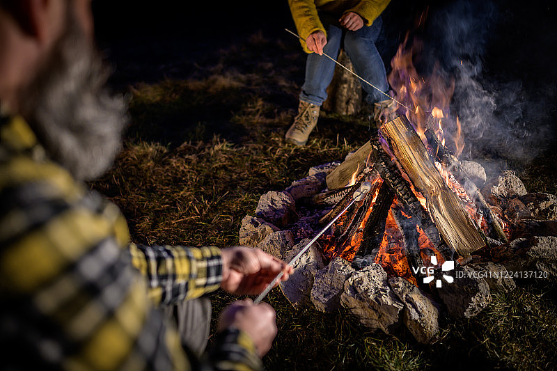 一对成熟的夫妇在篝火上烤棉花糖图片素材