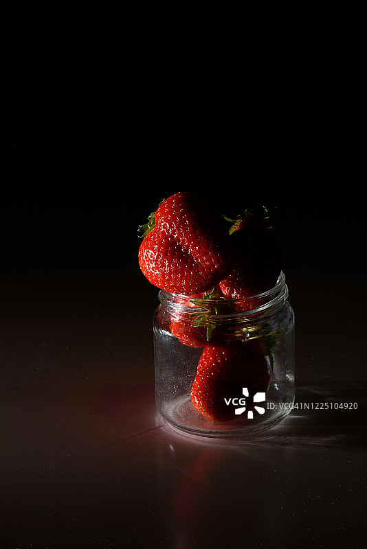 新鲜有机草莓孤立在黑色背景。天然产物的交付。包装由有机草莓。图片素材