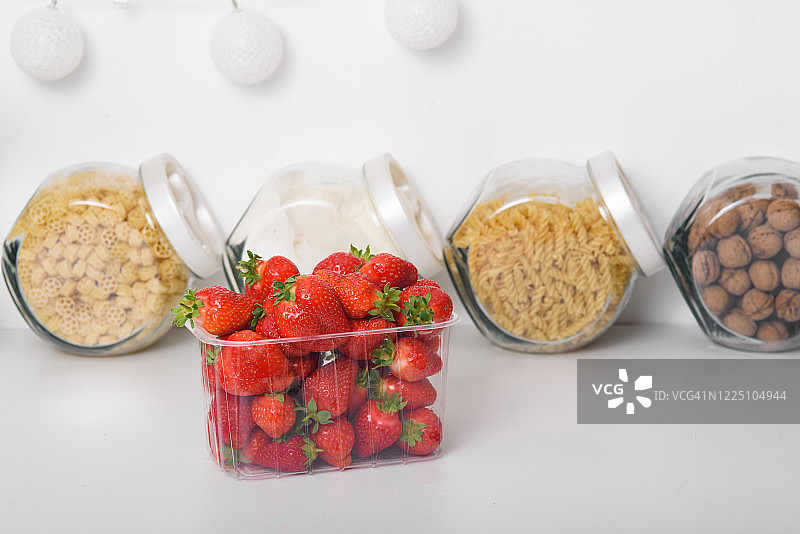 厨房里的塑料盒子里装着新鲜的有机草莓。有机产品的交付。有机草莓的包装。图片素材