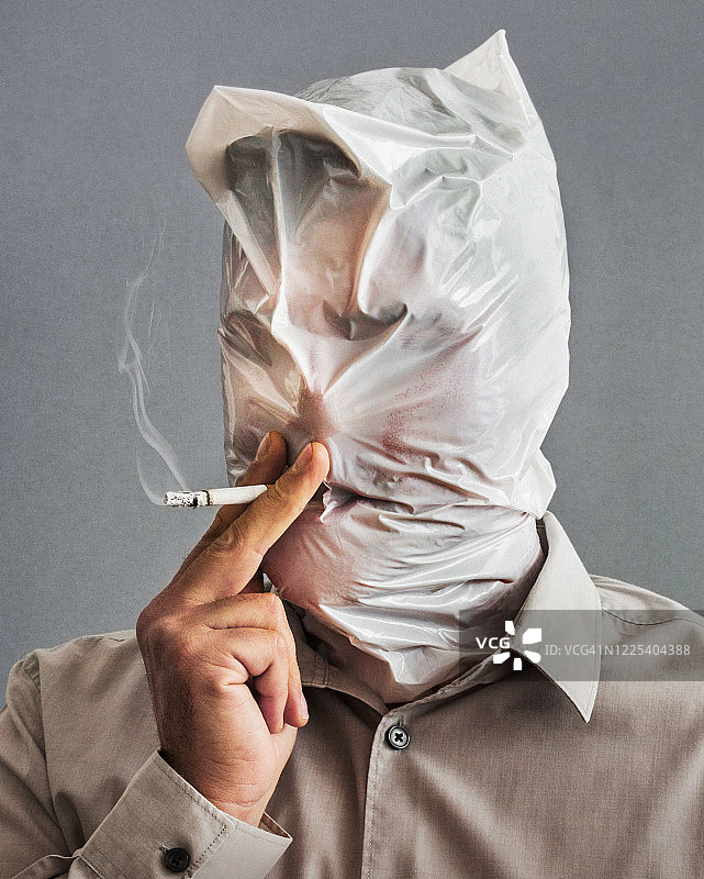吸烟者在吸着烟，头和脸都被塑料袋遮住图片素材
