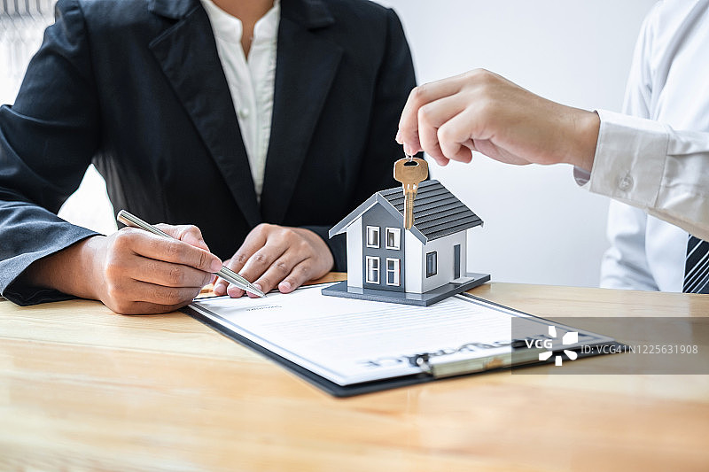 房屋保险和房地产投资概念，销售代理在签订协议合同和批准的物业申请表后给新客户房子钥匙图片素材