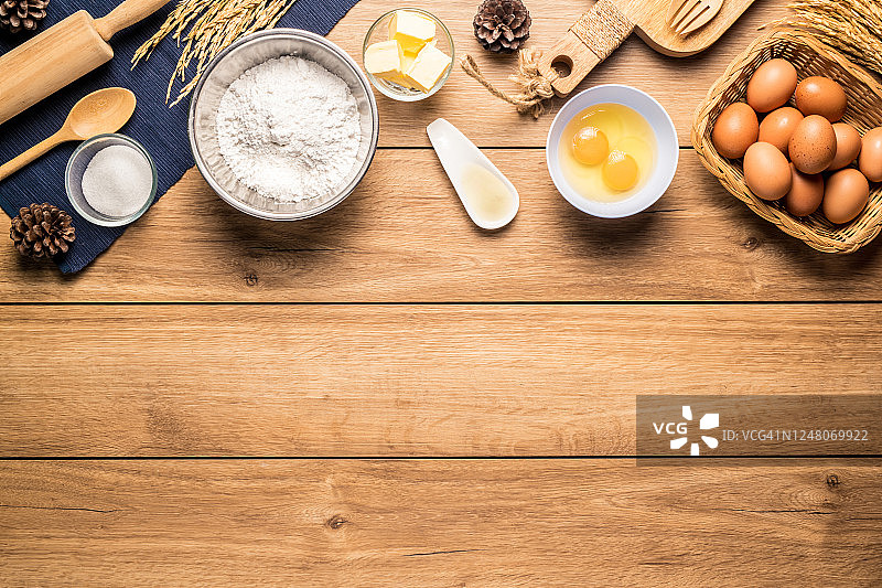 制作蛋糕的材料图片面包店周围，如鸡蛋，面粉，糖，黄油，粉和设备的制作在木地板上，俯视图，有复制空间。图片素材