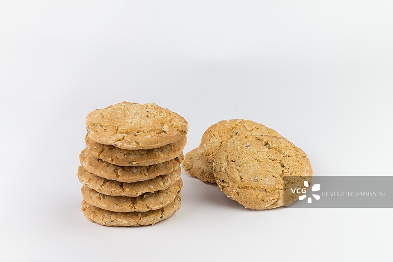 麦片饼干堆在几块饼干上面，背面有三块饼干，饼干是棕色的，图像中物体旁边有一块空白区域，背景是白色的图片素材