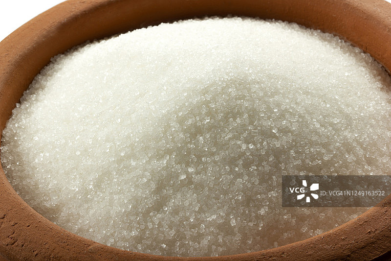碗里的砂糖。精制蔗糖的结晶。甜蜜的可溶性碳水化合物。蔗糖，葡萄糖和果糖的双糖。图片素材