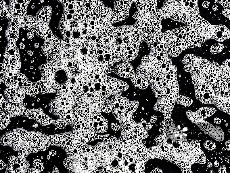 由黑色背景上的肥皂泡形成的纹理的完整框架。图片素材