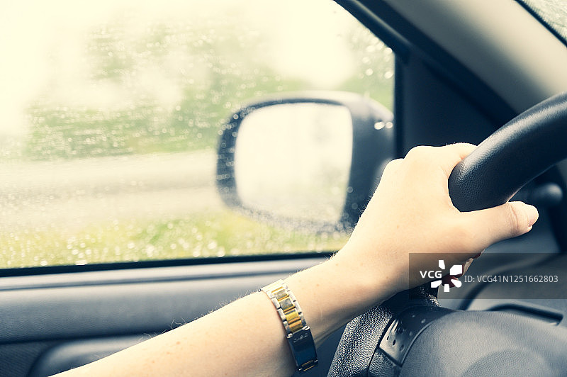 女人的手在雨天开车。图片素材