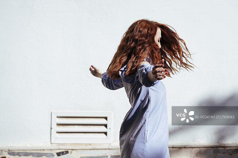 红发女子高举双臂在户外跳舞图片素材