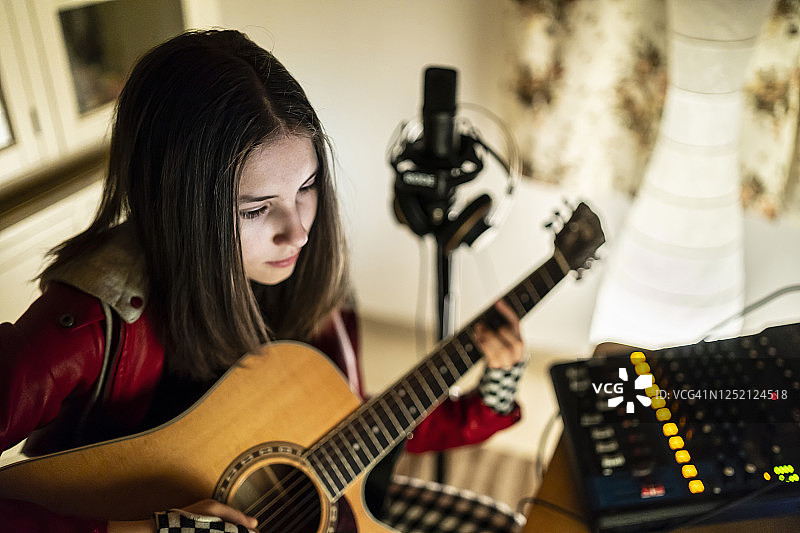 一个十几岁的女孩在家里弹吉他图片素材