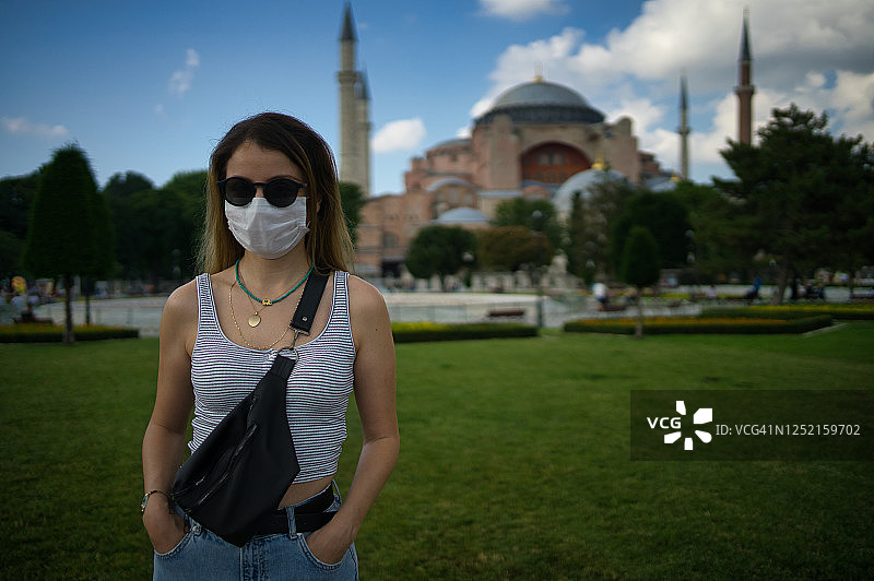 因为一种冠状病毒，一名妇女戴着医用口罩在圣索菲亚大教堂前摆姿势图片素材