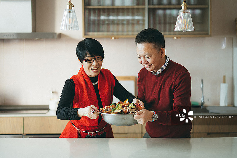 资深亚洲夫妇拿着美味的自制传统中国菜，与家人分享农历新年团圆饭图片素材