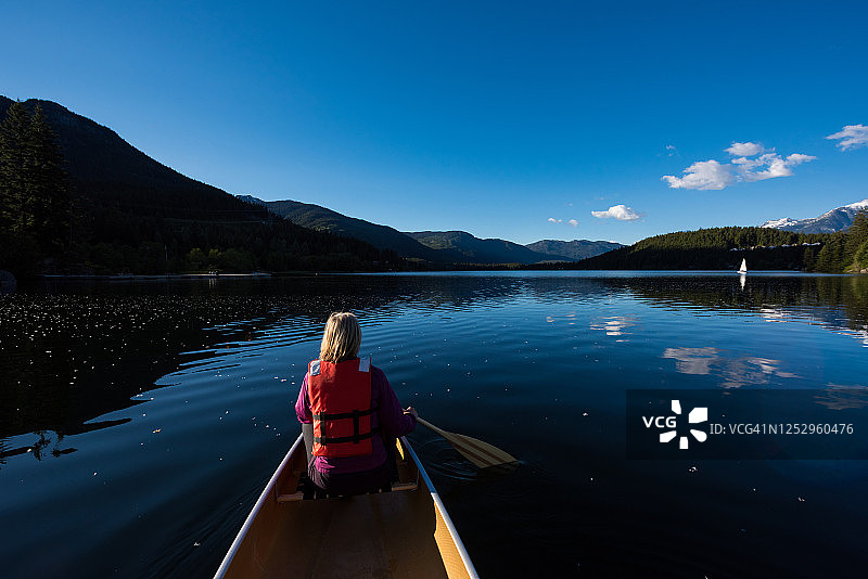 在山上的湖上划独木舟的女人图片素材