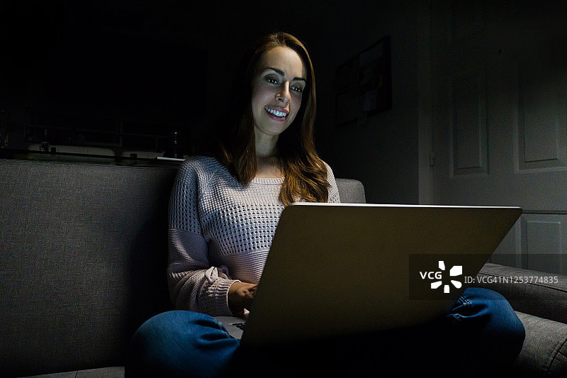 一名女子晚上在家里用笔记本电脑看社交媒体图片素材