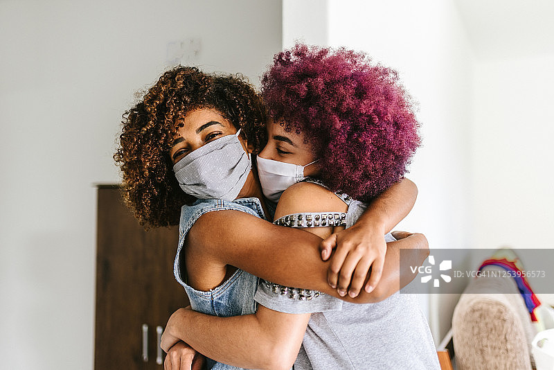 新冠肺炎:两个卷发女人拥抱在一起图片素材