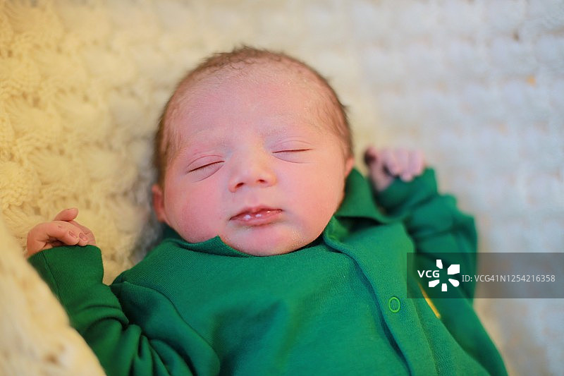 新出生的婴儿男孩与绿色婴儿服在一个白色毯子图片素材