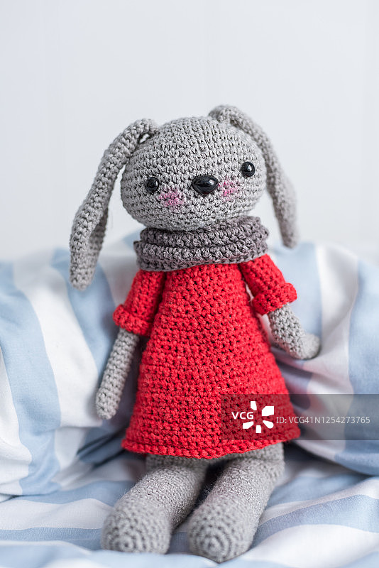 手工钩针娃娃在红色和围巾在床上图片素材
