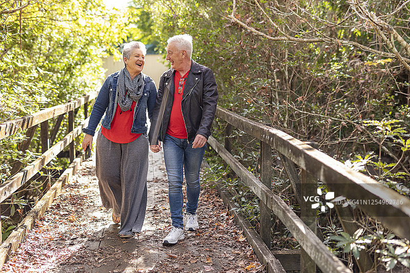 快乐的老夫妇在森林里走过一座木桥图片素材