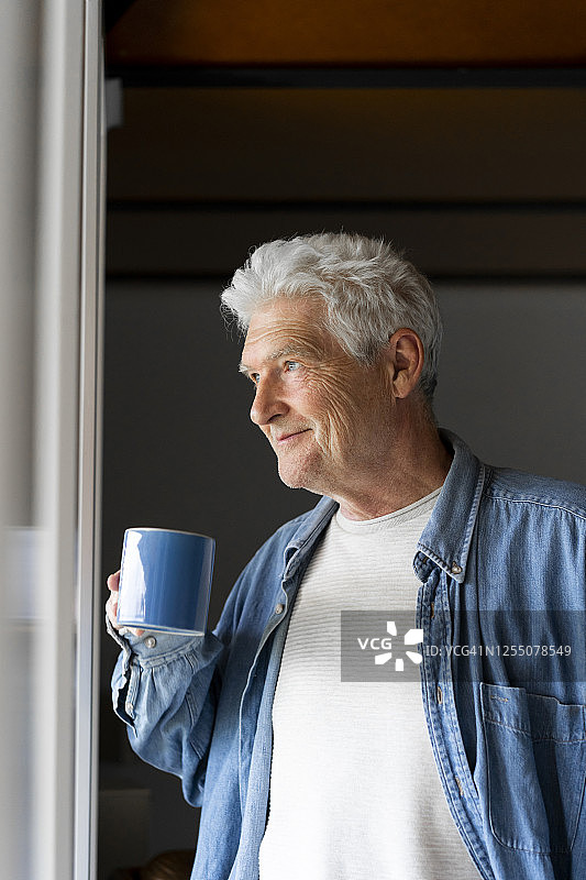 在家靠窗边喝咖啡时，体贴的老人微笑着图片素材