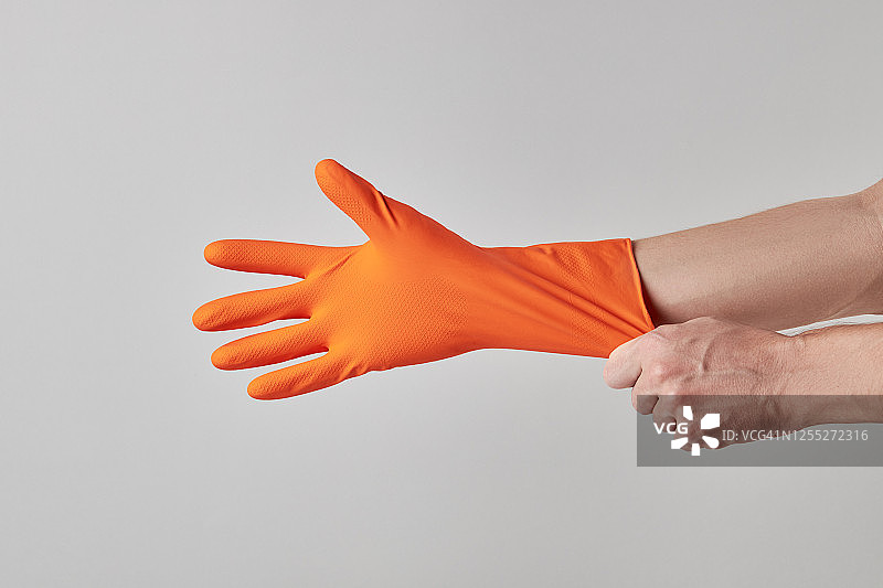 清洁服务理念。清洁人员戴橙色或黄色防护手套。灰色背景。副本的空间。图片素材