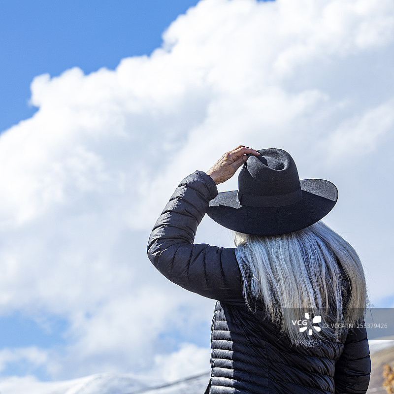 在蓝天白云的映衬下，戴着帽子的妇女的肖像图片素材