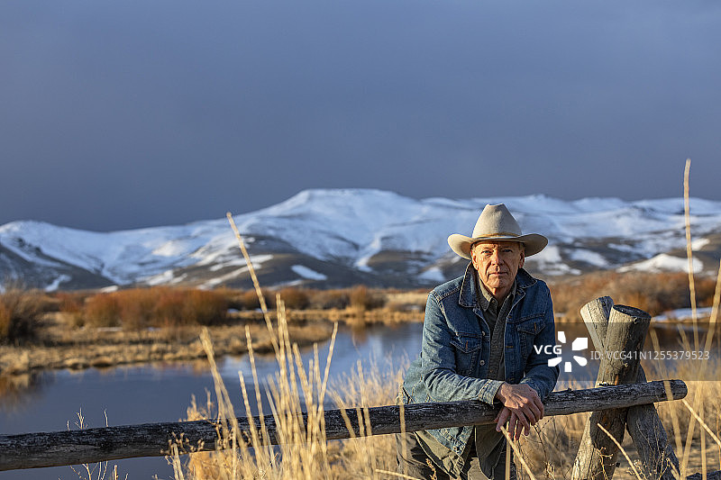 美国，爱达荷州，太阳谷，戴牛仔帽的老人靠在篱笆上图片素材
