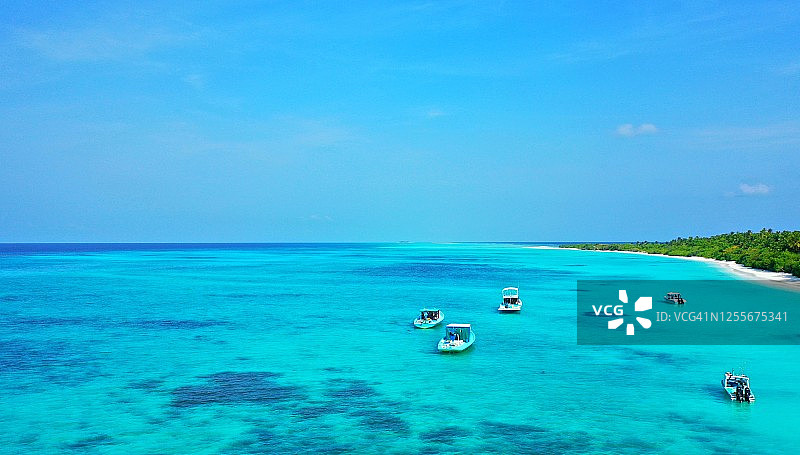 鸟瞰马尔代夫的一个热带岛屿，白色沙滩上有棕榈树图片素材
